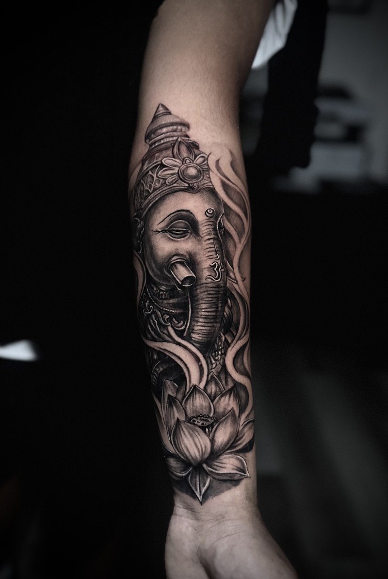 Black and grey image of Ganesha with ornamental details and a lotus flower.